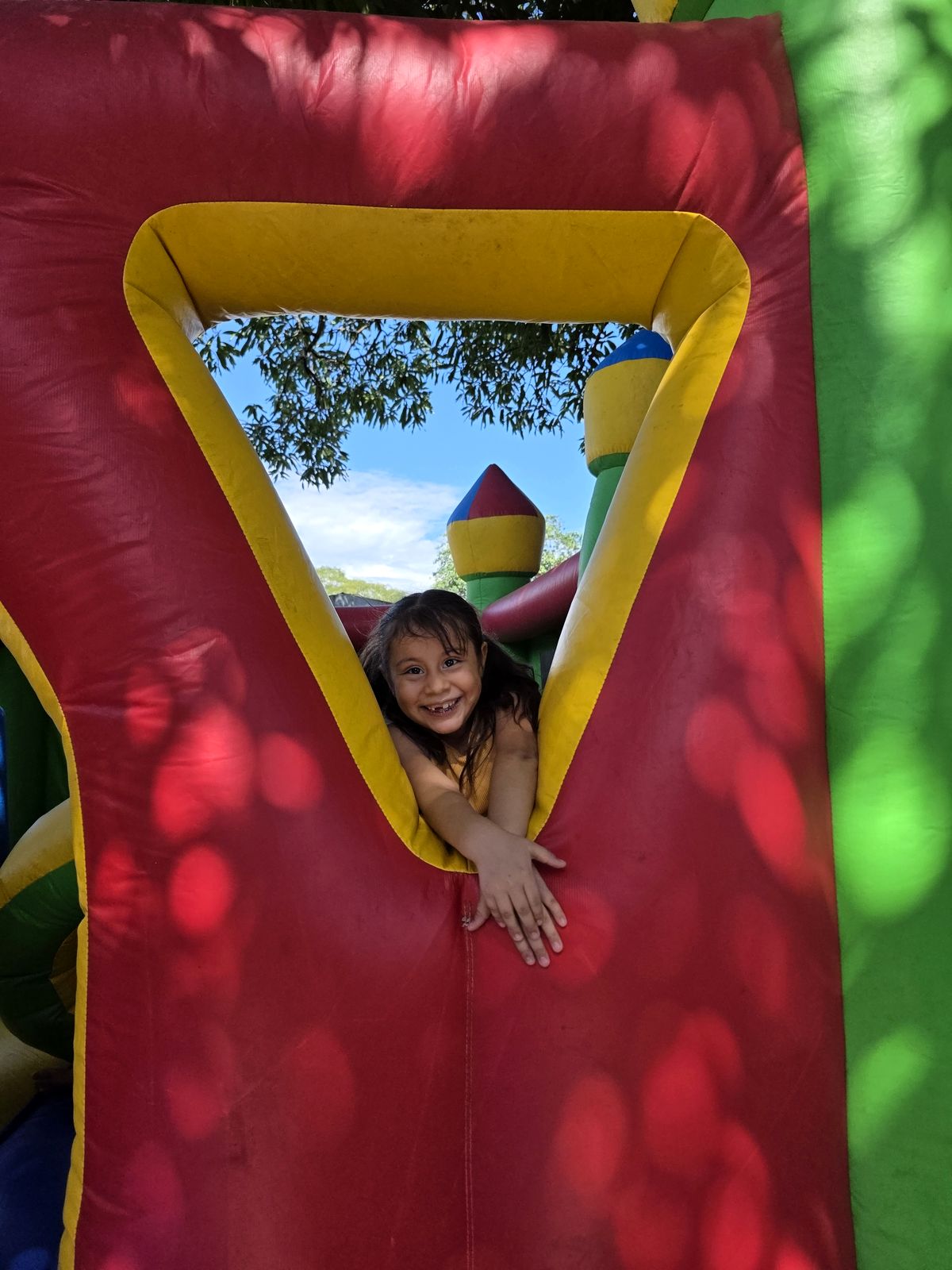 Niña asomándose sonriente desde el inflable