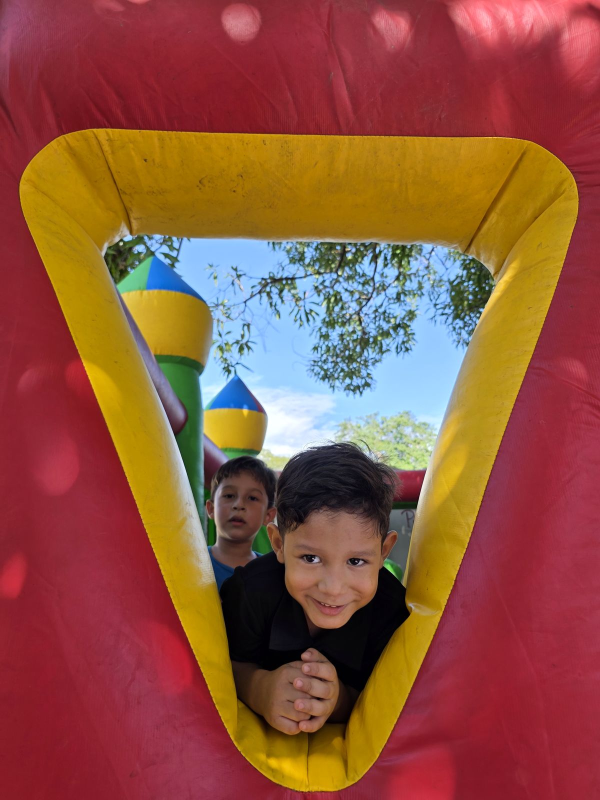 Niños sonriendo desde la ventana del inflable