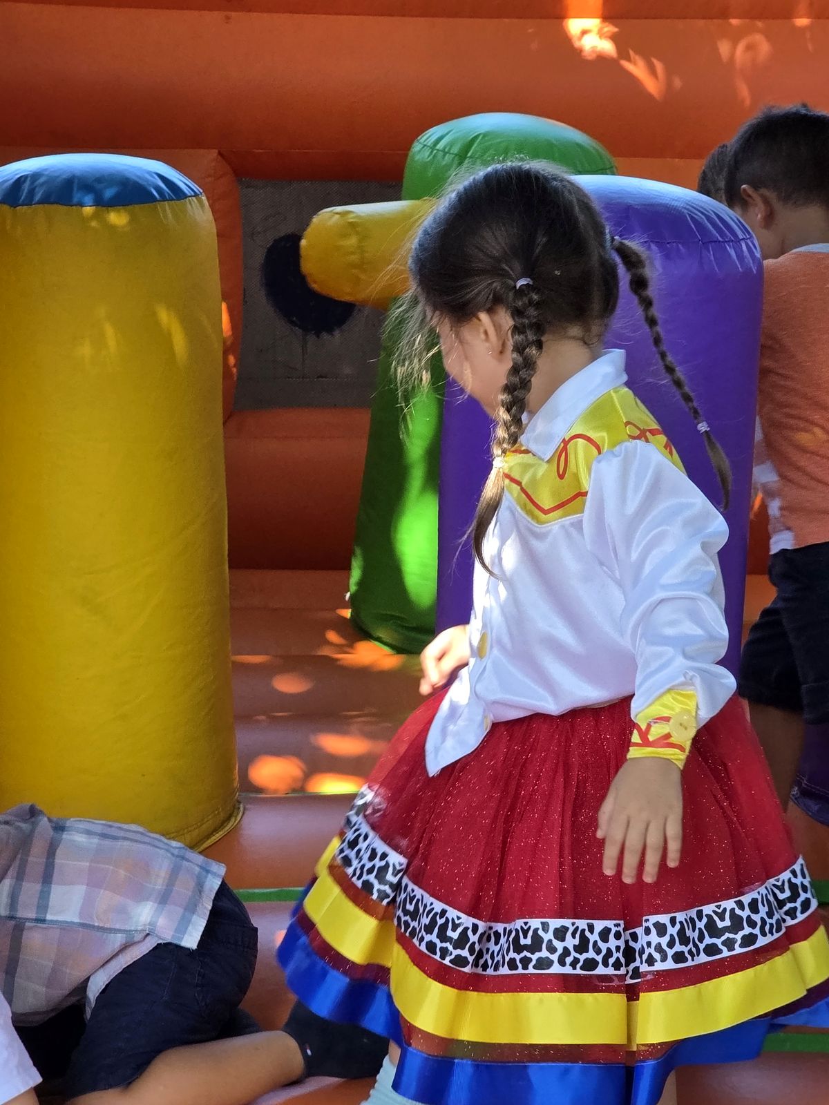 Niña con traje colorido descansando entre juegos